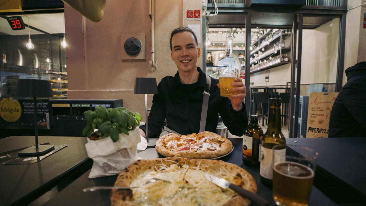 Man smiling with Italian pizza and craft beer in Palermo
