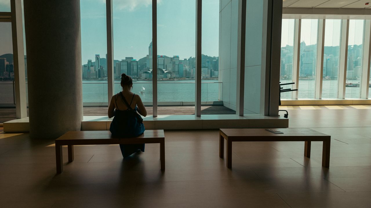 Woman sitting at Hong Kong Museum of Art with view of skyline