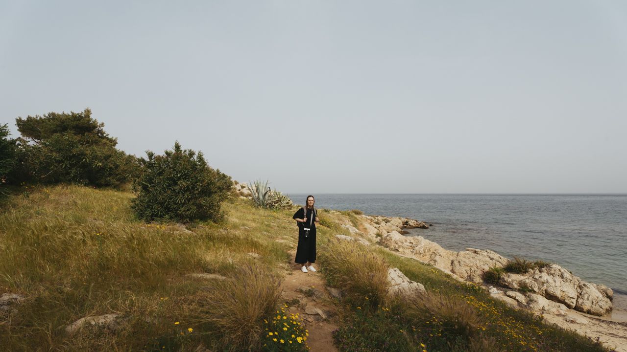 Women walking on the grass in front of the ocean at Santa Flavia