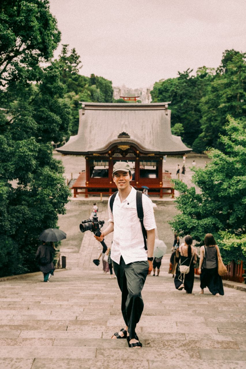 Man standing with a camera on the stairs of Tsurugaoka Hachimangu, Kamakura.