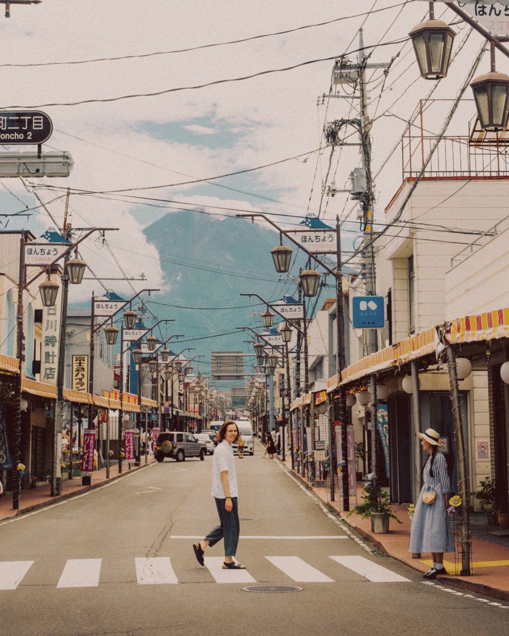 A man crossing Yamanashi Street with a view of Mount Fuji.