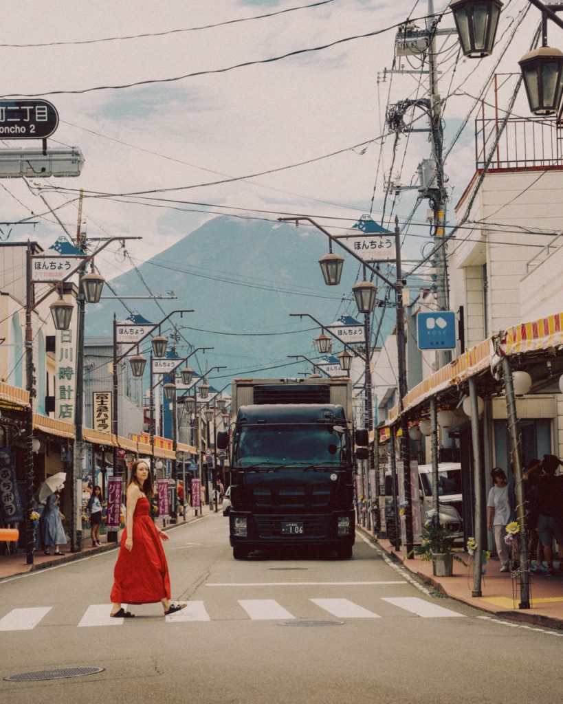 A woman in a red dress crossing Yamanashi Street with Fuji view.