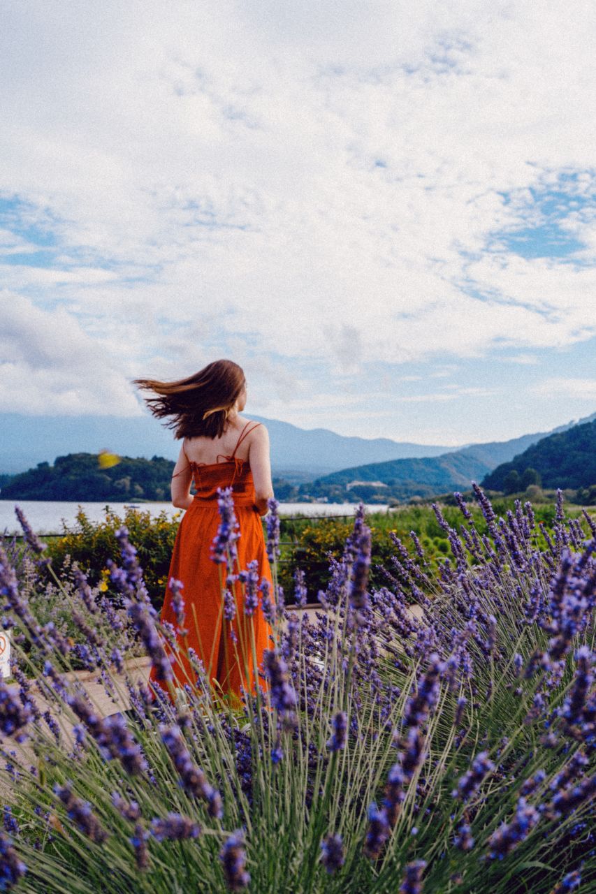 Woman in red dress in vibrant lavender field with Mount Fuji view at Oishi Park.