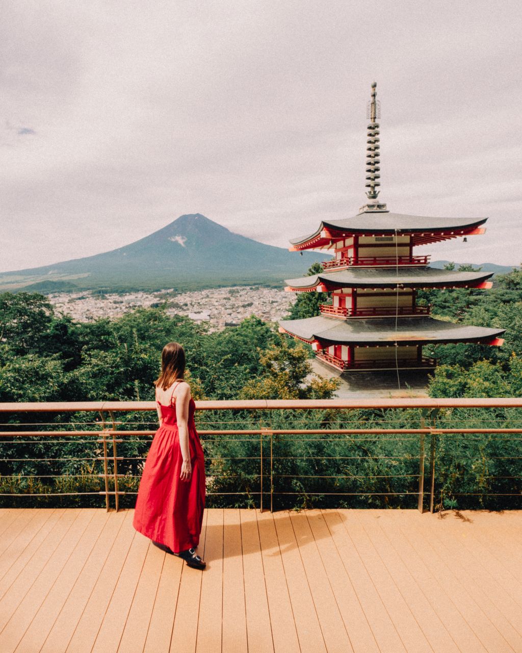A woman in a red dress watching Chureito Pagoda and Mount Fuji in Japan.