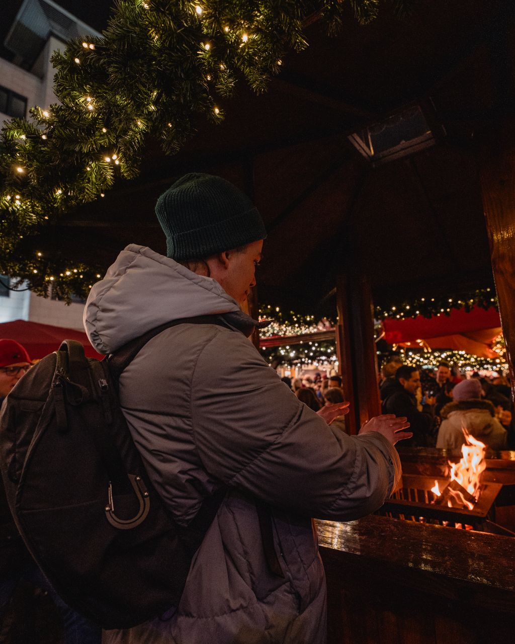 A man warming his hands at the Rossmarkt Christmas Market.