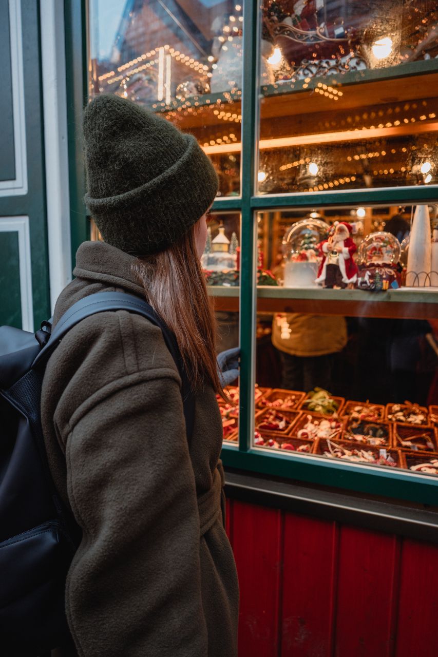 A woman looking at a window of a red stand at Römerberg market.